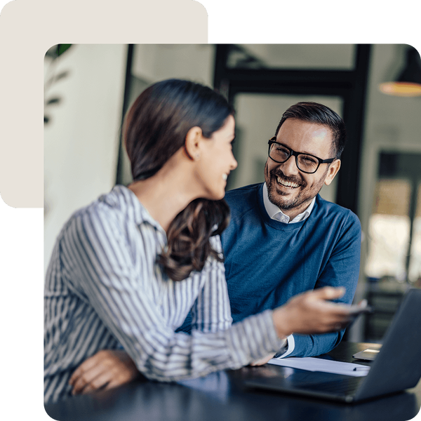 Persönliches Gespräch zu Versicherungsfragen zwischen einer Frau und einem Mann an einem Tisch mit Notebook.