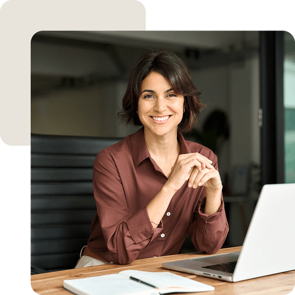 Frau sitzt am Schreibtisch mit Notebook und Notizbuch