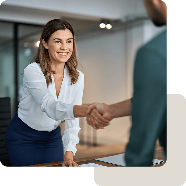 Vertrauensvolles Beratungsgespräch mit Handschlag wischen einer Frau im Business-Outfit und einem Mann im Anzug.